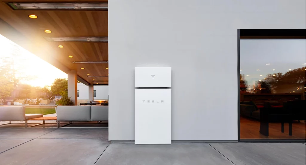 Tesla Powerwall Plus installed on the exterior of a contemporary home with a large covered patio