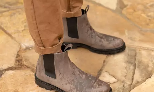 person wearing leather nisolo shoes and burnt orange pants standing on a stone patio